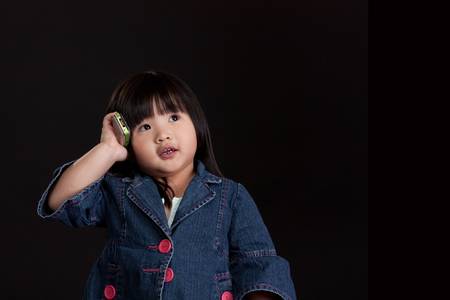 Cute little chinese girl using mobile phoneの写真素材