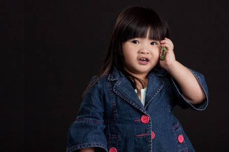Cute little chinese girl using mobile phoneの写真素材
