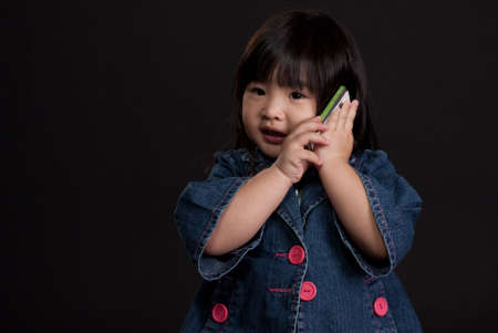 Cute little chinese girl using mobile phoneの写真素材