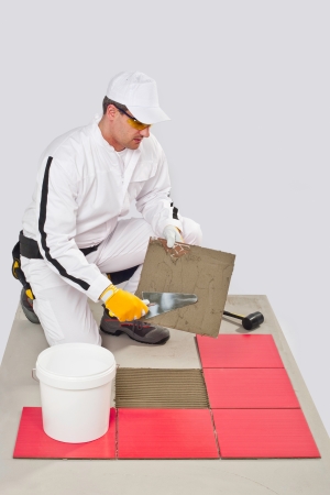 Worker Applies with Trowel Tile Adhesive on a Floor Red Tileの写真素材