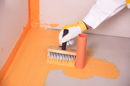 builder brush applied waterproofing on the floor of the bathroom pipe cornerの写真素材