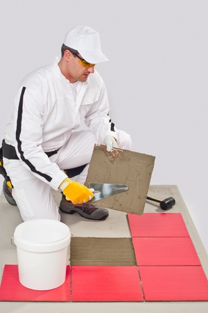 Worker Applies with Trowel Tile Adhesive on a Floor Red Tileの写真素材