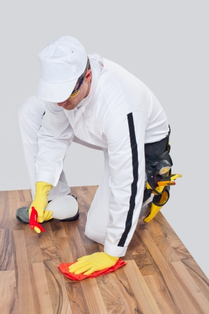 worker cleans with towel and spray wooden floor before tillingの写真素材