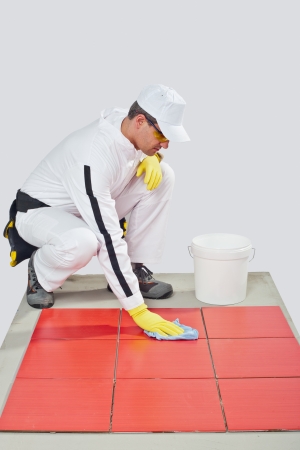 worker with yellow gloves and blue towel clean red tilesの写真素材