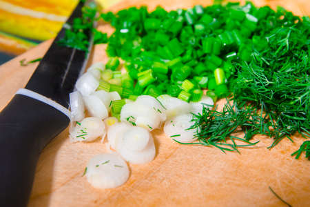 Cutting fresh onions and dill for the preparation of vitamin salad.の写真素材