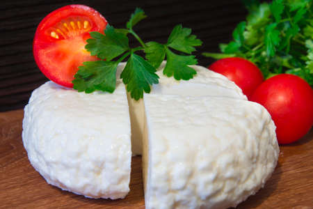 Young oak cheese cutting board with tomatoes and parsley. Mozarella for pizzas and salads.の写真素材