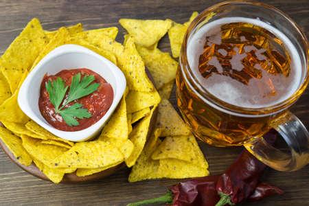 Nachos corn chips with classic tomato salsa. Fresh cold beer is perfect with savory snacks.の写真素材
