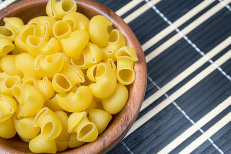 Uncooked pasta in wooden bowl. Preparation for cooking.の写真素材