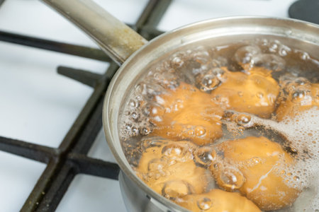 Chicken eggs boil in water. Pan with the product on a gas stove.