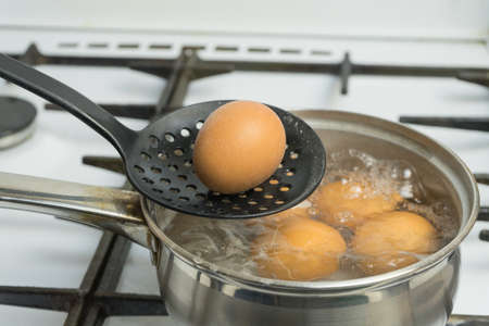 Chicken eggs boil in water. Pan with the product on a gas stove.