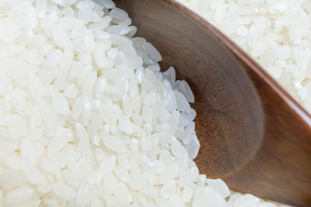 Photo of raw rice grains that are typed with a wooden spoon.の写真素材