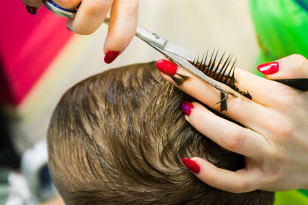 The hairdresser cuts the child. Haircut close-up...の写真素材