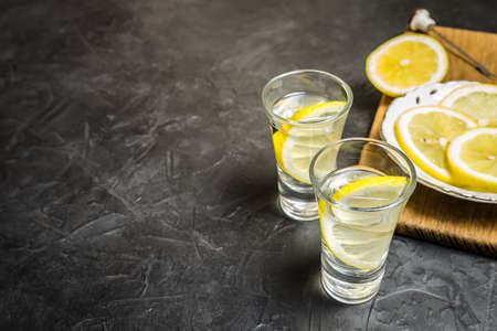 Glass of vodka. And lemon slicing on a plate.の写真素材