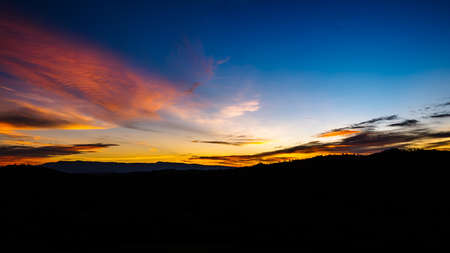 The Sunset on the mountains. Orange-yellow sunshine on a hill Blue sky in the summer evening.の写真素材