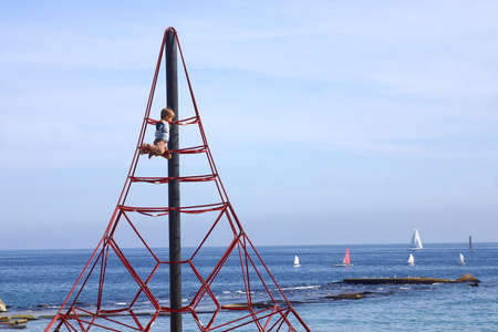 boy playing at the top of a playtower at the beach of the city of Barcelona, Catalunya, Spain, Europeの写真素材