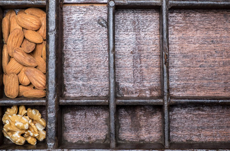 Almonds and hazelnuts in wooden bowls on wooden background
