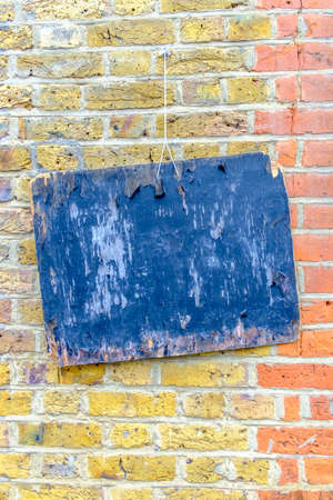 Close-up of blue painted wooden board hanging on colorful red and yellow brickwall.の写真素材