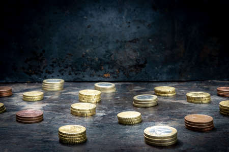 mosaic with a regular pattern made up of euro coins on a dark black background with ripped metal detailsの写真素材