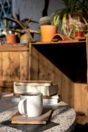 white cup with cappuccino coffee and books on an old table with a background of old rustic woodsの写真素材