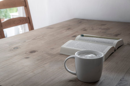 cup with coffee and a book on a rustic wooden table