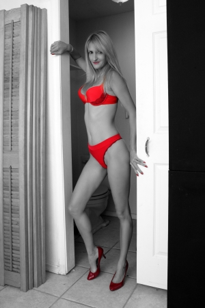 A hot blonde stands in the doorway of her bathroom, wearing a nice red bra-and-panty set with red heels   Monochrome with selective coloring on the lingerie, shoes, and lips の写真素材