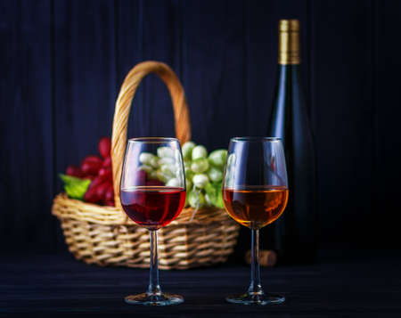 Glass of red and white wine with a de-focused bottle and fruits on backの写真素材