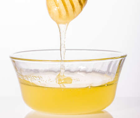 Fresh honey dripping off wooden dipper closeupの写真素材