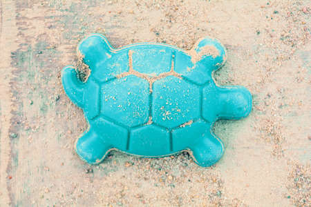 Dirty children plastic turquoise toy in the form of a turtle on the sandの写真素材