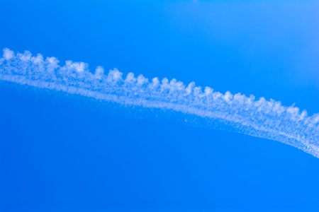 Deep blue sky with a white airplane trail