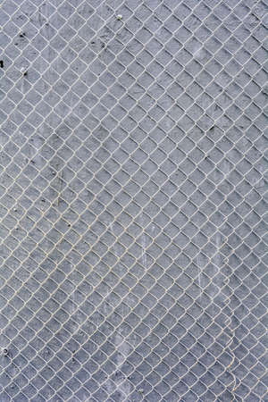 Fence mesh urban background. Wire iron fence on gray painted wallの写真素材