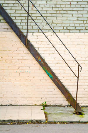 Brick wall of a building with a rusty metal staircase leading to the second floorの写真素材