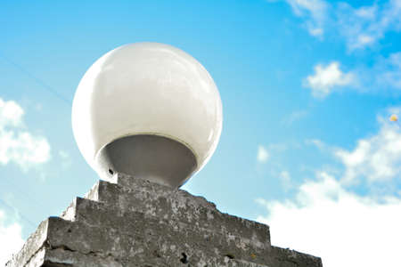 Turn off the white street lamp in city, cloud and blue sky in afternoon, energy conservation. The exterior round glass lamp on the stone basementの写真素材