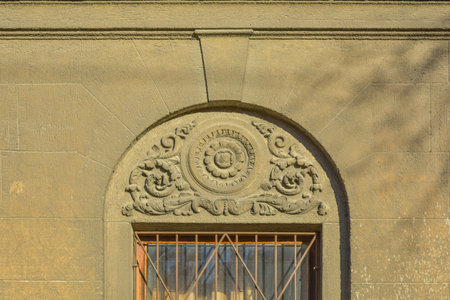Window with stucco molding with flower ornament above. Decorative bas relief with floral pattern on...