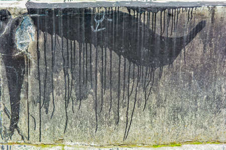 Texture of dirty destroyed concrete wall with black paint and dirt leaks. Old concrete texture with exfoliated layerの写真素材