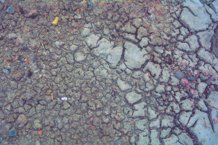 Dry mud ground with crack texture and granite gravel. Dry dirty soil on summer landscape. Cracks on...