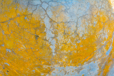 Yellow and gray cracked concrete texture. Rough surface with yellow painted spots. Old weathered...
