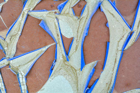 Texture of old bursting film on concrete wall. Red cracked protective film with twisted edges with blue wrong side. Damaged peeling wall covering, rolled along edges of cracks in rollsの写真素材