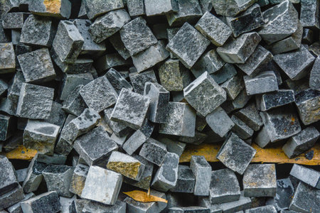 Pile of black natural stone cubes for making outdoor pavement tiles. Chaotic stack of broken road...