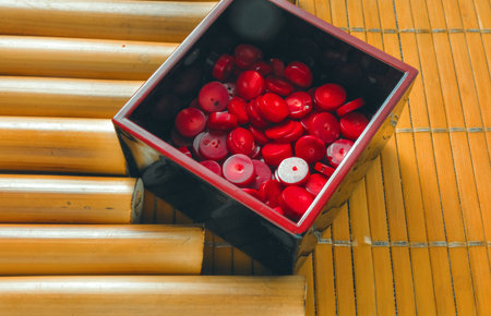 Bamboo sticks and bamboo napkin with red coral beads. Traditional bamboo pad with parts of dry...