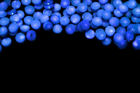 Frame of natural blue coral flat circled beads isolated on a black background. Coral beads as blue blood cellsの写真素材