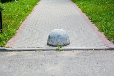 Element of sidewalk design and protection from car parking on streetwalk pavement. Gray rustic rough...