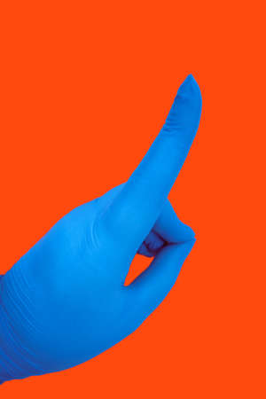 Human hand in latex blue medical glove isolated on orange with gesture. Protection conceptの写真素材
