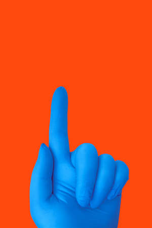 Human hand in latex blue medical glove isolated on orange with gesture. Protection conceptの写真素材