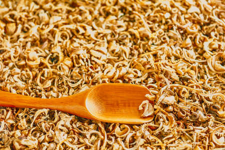 Wooden spoon on heap of scattered dry marigold seeds - healthy flowering plant for traditional medicineの写真素材