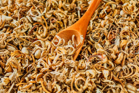 Wooden spoon on heap of scattered dry marigold seeds - healthy flowering plant for traditional medicineの写真素材