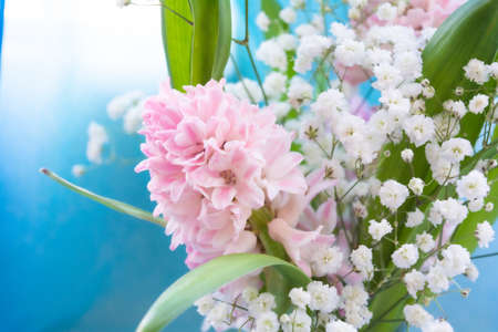 Bouquet of Beautiful pink Hyacinth with green leaves and branches with little white flowers of Gypsophila. Close-up spring Hyacinth flowers. Floral wallpaperの写真素材