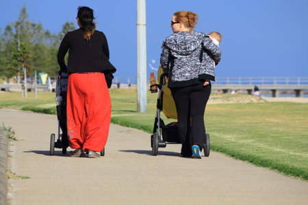 people walking with prams along the beachのeditorial素材