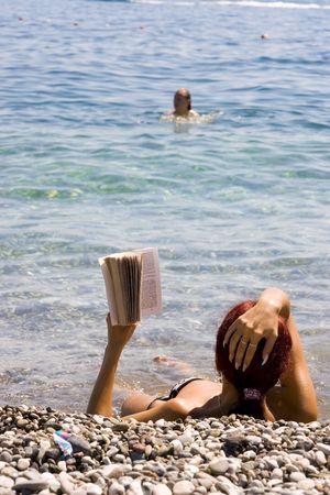 Beautiful girl relaxing by the seaside and reading a bookの写真素材