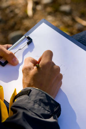 man sitting and drawing picture in nature with pencilの写真素材