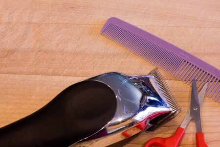 An image of hair clippers, comb and scissors on a wood background.の写真素材